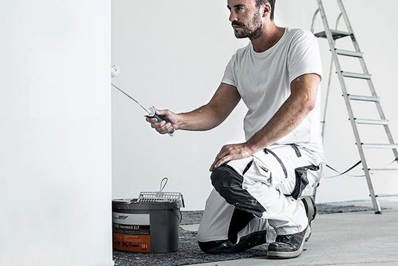 Mann streicht Wand mit Polyr